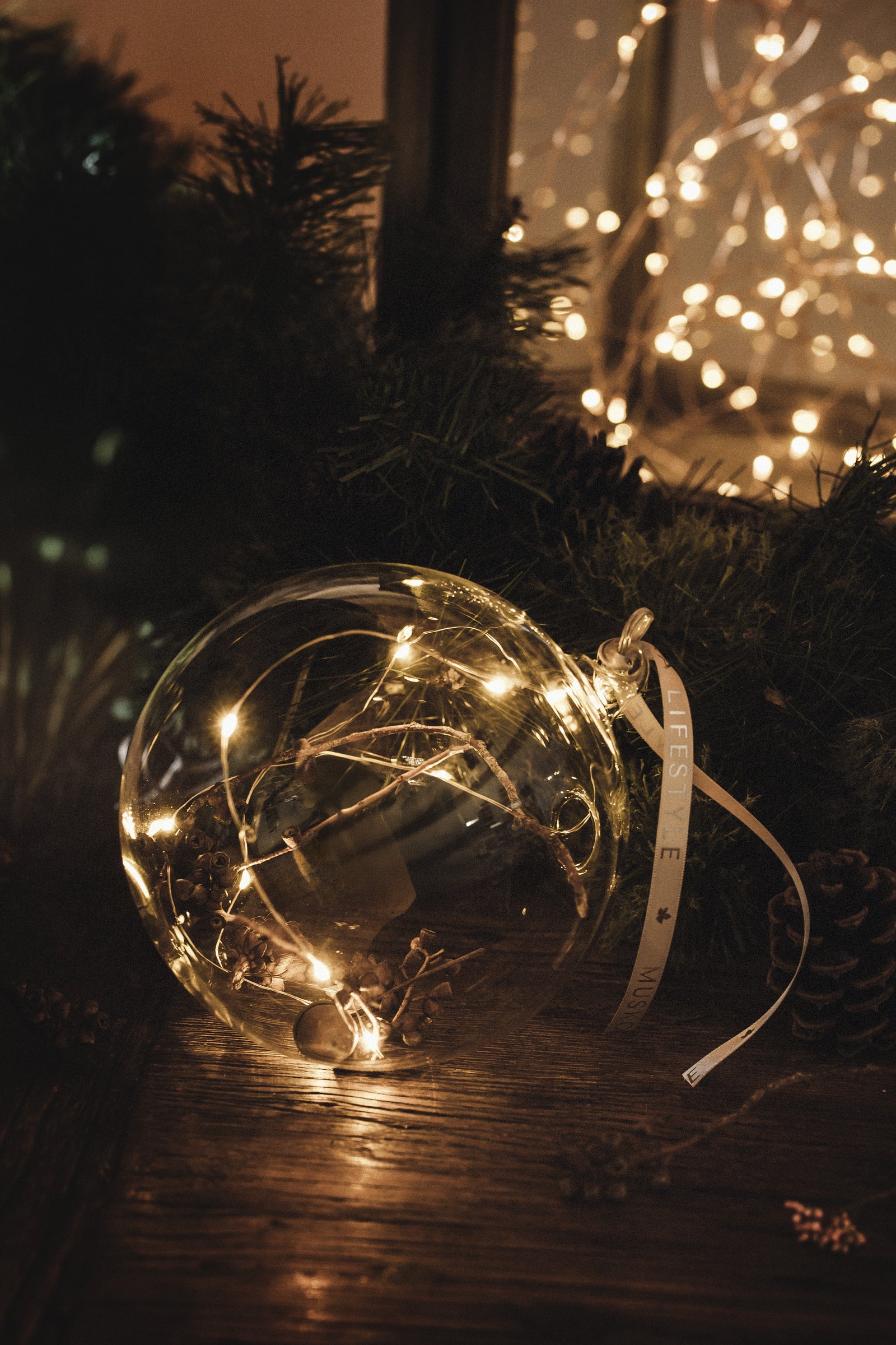 Decorative festive globe with pinecones,acorns and seedlights inside the glass orb. Crafted wooden toggle holds the battery unit.